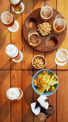 Wooden table filled with various beers, nuts, and potato chips, viewed from above. Concept of party, celebration, leisure time, Oktoberfest