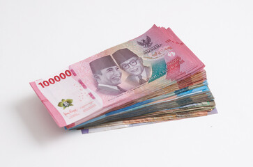 A stack of various Indonesian rupiah banknotes on a white background. Selective focus
