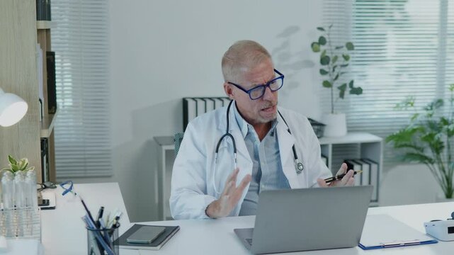 The doctor takes case consulting discuss with another and interview the patient's history and symptoms and explain discuss treatment method to patient via remote video conference on laptop.