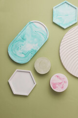 Plaster geometric shapes, trays on purple green background. Top view