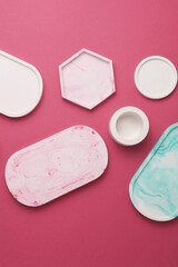Plaster geometric shapes, trays on pink background. Top view