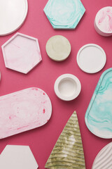 Plaster geometric shapes, trays on pink background. Top view