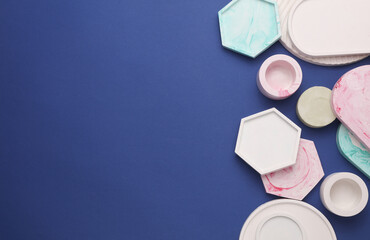 Plaster geometric shapes, decorative trays on blue background. Top view. Copy space