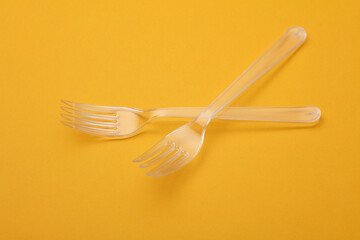 Transparent plastic forks on a yellow background