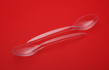 Transparent plastic spoons on a red background