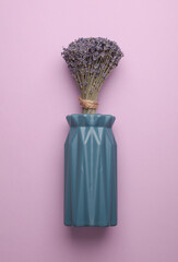 Dry eucalyptus flowers in vase on a purple background. Top view