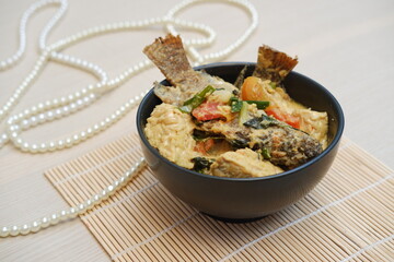 Fried fish with curry in a bowl on a bamboo mat.