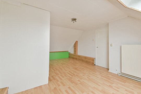 Empty attic room with wooden floor and white walls