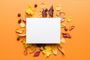 Autumn composition with paper blank and dried leaves on table. Flat lay, top view, copy space