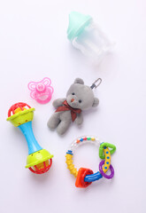 Toys for newborns, feeding accessories on a white background. Flat lay