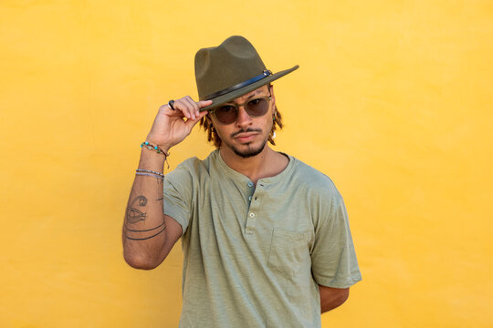 Fashionable man with dreadlocks against a yellow background