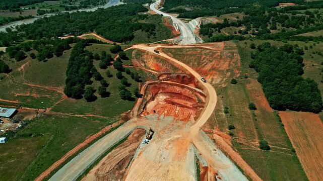 Open quarry with orange colors and working heavy machinery, aerial view