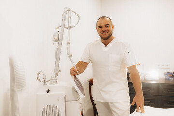 Portrait of the Professional Surgeon Looking Into Camera and Smiling after Successful Operation. In the Background Modern Hospital Operating Room.