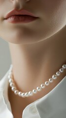 A close-up view highlights a smooth neck adorned with a single strand of lustrous pearls, complementing a classic white shirt