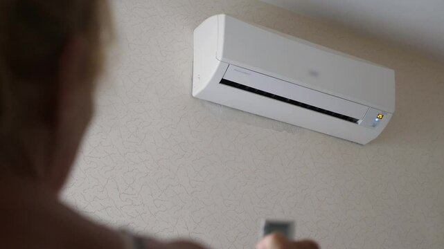 Senior woman using remote control to operate air conditioner