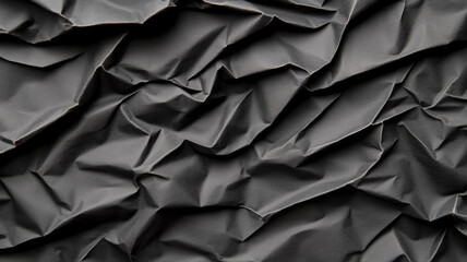 Obraz premium Heavily wrinkled black paper background with deep creases and a textured gritty surface 