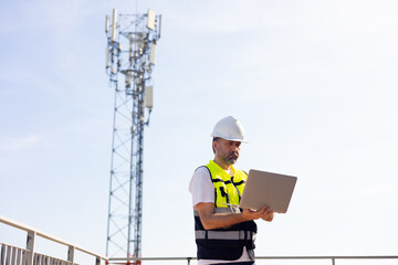 communication pole. Communications engineer checking internet signal on laptop computer at...