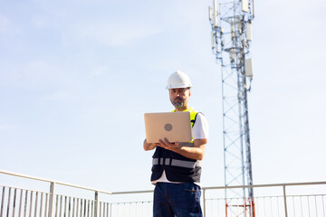 communication pole. Communications engineer checking internet signal on laptop computer at...