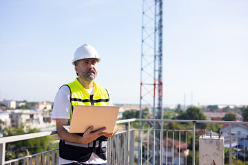 communication pole. Communications engineer checking internet signal on laptop computer at...