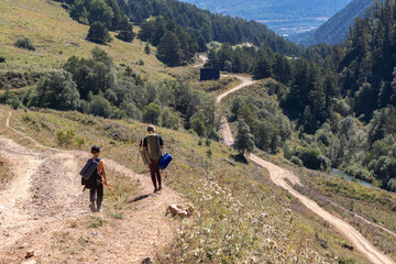 Obraz premium Mother and son tourists descend from the mountain. Focus on background