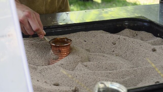 Process of making aromatic coffee brewed in hot sand - turkish coffee brewing in cezve.
