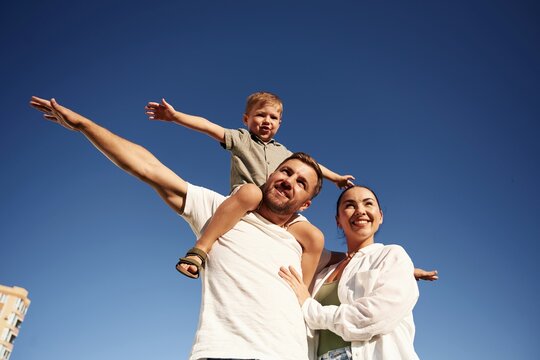 Bright blue sky, against it. Mother and father are with son outdoors on the field