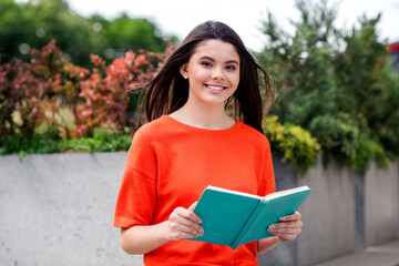Fototapeta premium Photo of attractive teen cheerful girl read book relax wear red garment having fun outside outdoors