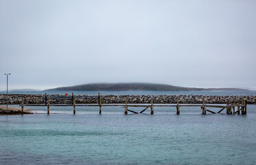 Eriskay ferry terminal on a cloudy summers day empty, Image shows a blue Atlantic ocean with a wooden pier used for mooring up docking ferries