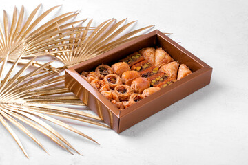 Eastern sweets in golden box on white background. Arabian baklava and ush-el-bul-bul dessert