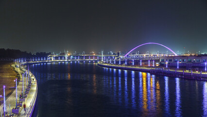 Two bridges over Dubai canal with a boat crossing under them timelapse.
