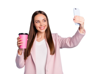 Portrait of cute cheerful lady using her cellphone making selfie holding mug with hot beverage wearing pink coat isolated over blue color background