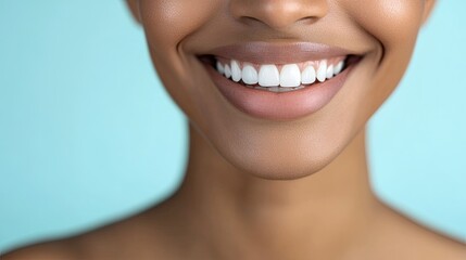 Obraz premium A close-up of a woman's beaming smile, highlighting her bright white teeth, with a light blue background adding a serene touch.