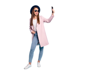 Full size photo of childish girl using her cell phone taking self photo having fun wearing eyeglasses eyewear topcoat denim jeans isolated over blue background