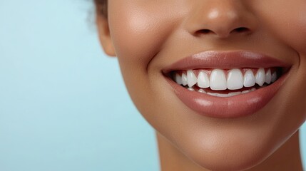 Fototapeta premium A close-up of a woman's bright white smile with perfectly aligned teeth, set against a light blue background, symbolizing dental care and confidence.