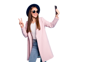 Portrait of cute content blog girl in eyewear eyeglasses making v-sign taking selfie having fun wearing pink stylish vercoat topcoat denim jeans isolated over blue background