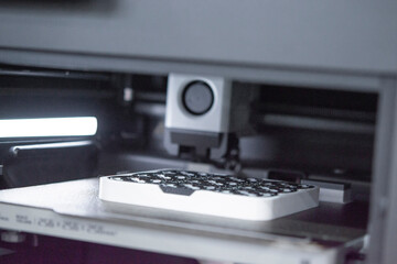 3D printer close up. A working 3D printer in process of printing object from molten plastic. 3D printer creating model by flowing liquid plastic from an extruder of printer. 3D printing technology