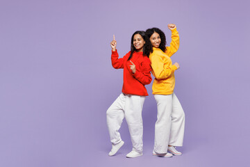 Full body side view two young little kid teen girls women they wears red yellow hoodie casual clothes do winner gesture celebrate clench fists isolated on plain purple background. Lifestyle concept.