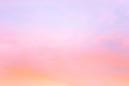 Twilight sky with effect of light in pastel pink, coral, orange, blue tones. Colorful sunset of soft clouds. Background