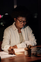 Young African businesswoman working at a desk in her office at night