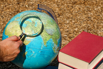 A man holds a magnifying glass and carefully examines the inscription on the globe. Several large...