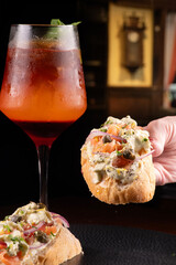 close up of female hand holding baguette sandwich with smoked salmon and cream cheese and seasoning...