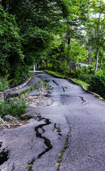 Collapsing bumpy asphalt road in need of repair, potholed road