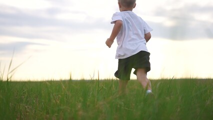 Boy and son running in nature. Father dad smile concept. A kid runs on the grass in a park. A boy and his son run through the grass in lifestyle a park.