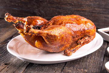 Peking Duck on a white plate served with fresh cucumber, green onions, cilantro and roasted wheaten chinese pancakes on black  wooden background. Chinese food. food concept.