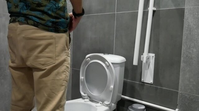 The process of a male person peeing in the toilet