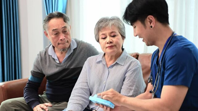 Senior couple get medical service visit from caregiver nurse at home while explaining on doses of vitamins and drug pill for health care and pension welfare insurance