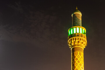 Illuminated minaret of Iranian Mosque (Imam Hussein Mosque) in Dubai, colorful Persian tiles facade...
