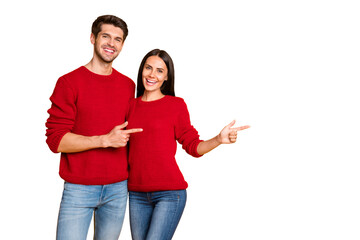 Portrait of charming spouses point at copy space recommend ads wear red pullover sweater denim jeans isolated over yellow background