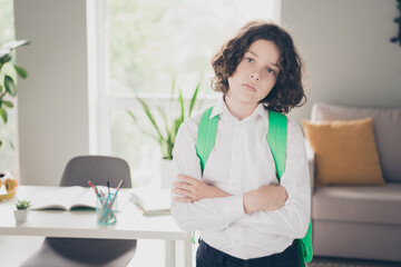 Photo of pretty sad tired boy schoolchild wearing white shirt going to school 1st september morning room indoors