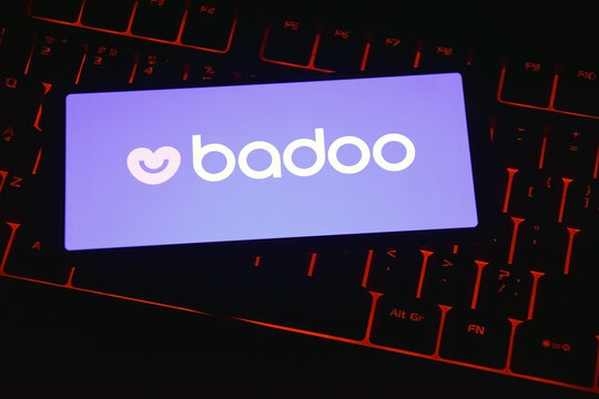 Badoo icon on smartphone screen on keyboard with red backlight close-up.